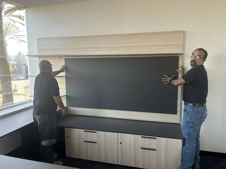 Installation team mounting the full-height wallboard panel in an executive suite: custom-specified to exact room dimensions and finished to match the contemporary palette.