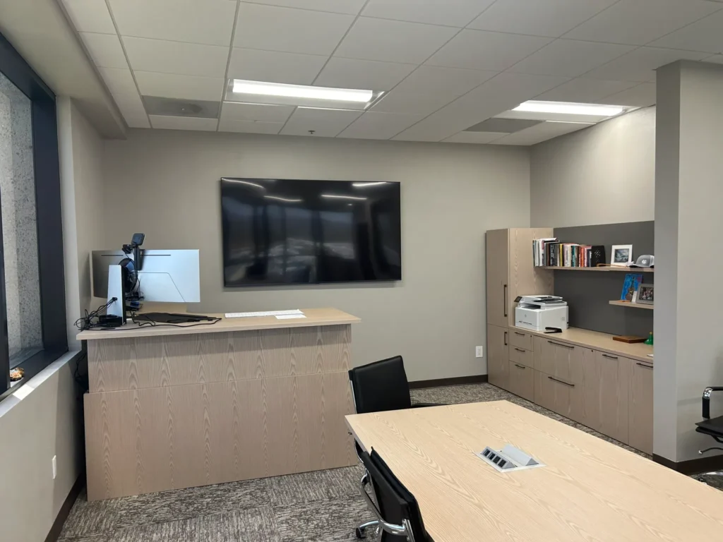 AFTER: Executive Height adjustable desk (showing in standing position) No legs are seen. Added meeting table, credenza, coat closet, printer station and coffee bar.